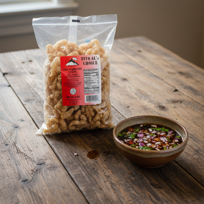 A clear plastic bag of Tito Al's Choice Chicken Breading Crumbs stands on a rustic wooden table next to a small bowl of dipping sauce.